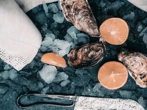 Ostriche fresche crude su ghiaccio con fette di limone, mollusco dell'Oceano Atlantico su asciugamano di lino — Foto Stock