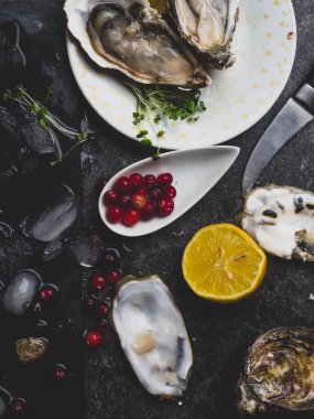 İstiridye kalbi tabakta limon, kızılcık, mikro yeşillik, bıçak, mermer kabuk şeklinde.