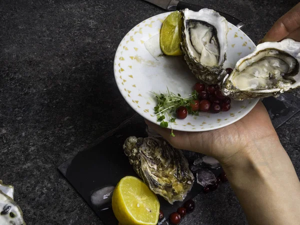 Ostra abierta en las manos, sobre un fondo de ostras abiertas, enfoque selectivo — Foto de Stock