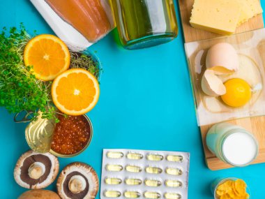 Mavi arka planda, kapsüllü D vitamini içeren ürünler, üst görünüm