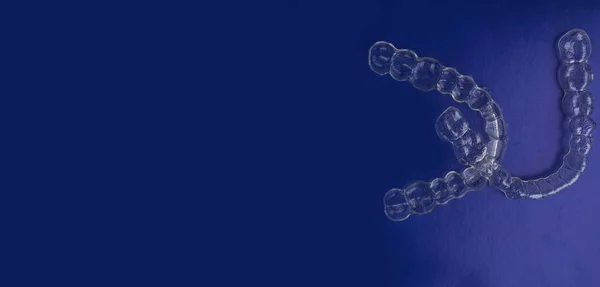 Dientes dentales invisibles soportes alineadores de dientes en el fondo azul de moda, abrazaderas de plástico retenedores de odontología para enderezar los dientes. Ortodoncia temporal extraíble enderezar — Foto de Stock