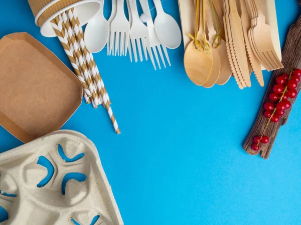 Ecological biodegradable and plastic disposable tableware for food on a blue background