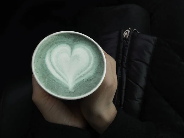 Mains féminines tenant une tasse écologique de matcha vert, latte art classique. Place vide pour le texte, espace de copie. Dépendance au café. Vue du dessus — Photo