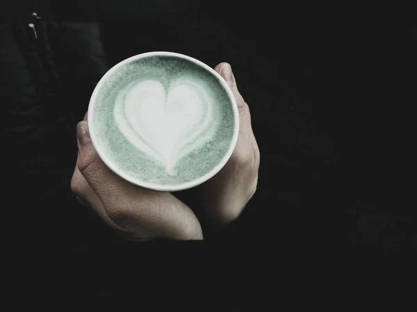 Manos femeninas sosteniendo taza ecológica de matcha verde, arte latte clásico. Lugar vacío para texto, espacio para copiar. Adicción al café. Vista superior — Foto de Stock