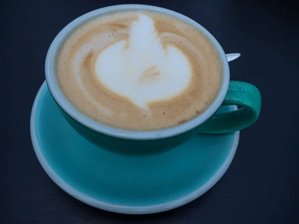 Arte latte en taza de café azul o taza sobre fondo de madera de moda — Foto de Stock