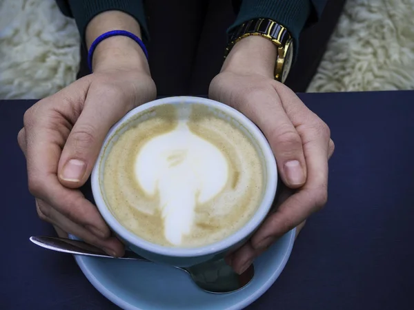 Γυναίκα κρατώντας ζεστό φλιτζάνι καφέ, με όμορφο σχήμα τέχνης, Closeup των γυναικείων χεριών και κούπα του latte — Φωτογραφία Αρχείου