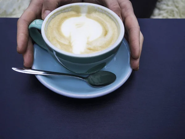 Γυναίκα κρατώντας ζεστό φλιτζάνι καφέ, με όμορφο σχήμα τέχνης, Closeup των γυναικείων χεριών και κούπα του latte — Φωτογραφία Αρχείου