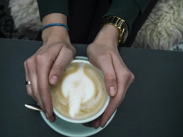 Žena drží horký šálek kávy, s krásným uměleckým tvarem, Detailní záběr ženských rukou a hrnek latté — Stock fotografie