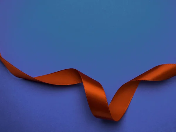 Red silk ribbon twisted on a trendy classic blue background, festive postcard, copy space — 스톡 사진