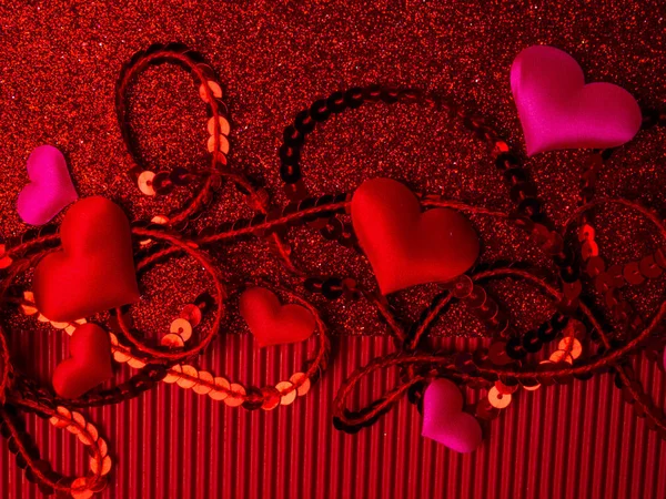 Hjärtan och paljetter på en glitter röd bakgrund, ovanifrån. Julkort för alla hjärtans dag eller bröllop. Design för vykort, kopieringsutrymme. — Stockfoto