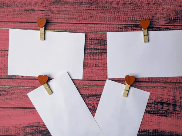 boş etiketleri taklit et ve ahşap kırmızı kalbi kumaş raptiyelerde asılı bir iple eski kaba ahşap duvarda