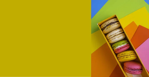 Kleurrijke macaroon koekjes in doos, stilleven, kleurrijke achtergrond. Platte lay stijl. — Stockfoto