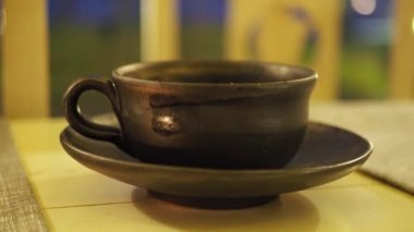 Clay cup of tea with hot steam, Chinese tea ceremony Asian wooden table, close up with selective focus