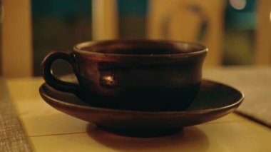 Clay cup of tea with hot steam, Chinese tea ceremony Asian wooden table, close up with selective focus