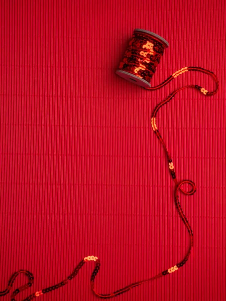 The spool of red sequins on a festive red corrugated background. — 스톡 사진