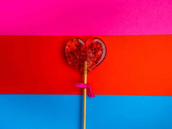 Einzelner herzförmiger Lutscher des Valentinstages auf buntem Hintergrund — Stockfoto
