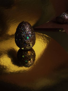 Yaratıcı kırmızı altın renkli paskalya yumurtası, bulanık bir yansıma ile lüks altın bir yüzey üzerinde. Bahar tatili