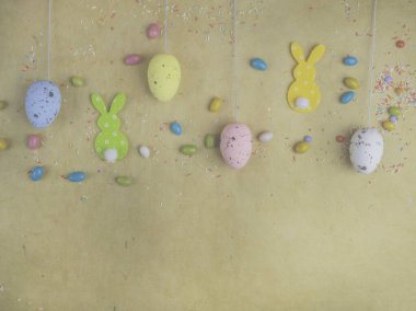 Oyuncak sevimli tavşan ve renkli paskalya yumurtaları, sarı arka planda lezzetli şekerler. Tavşancık. Komik dekorasyon. Mutlu Paskalyalar