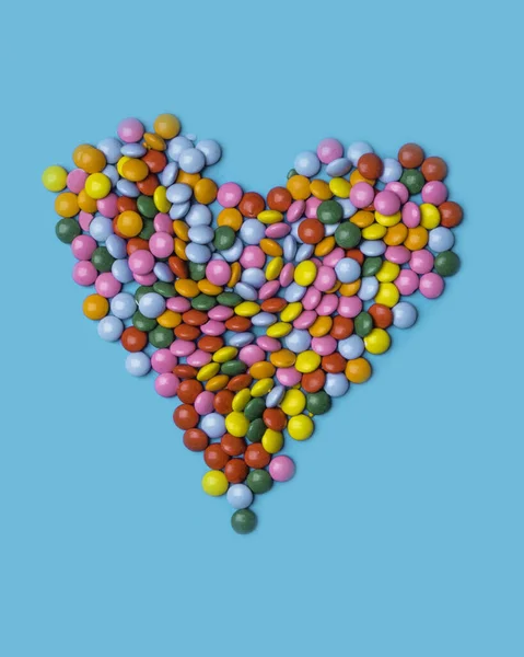 Colorful candies arranged as heart on blue background for valentines day, birthday, party card — Stock Photo, Image