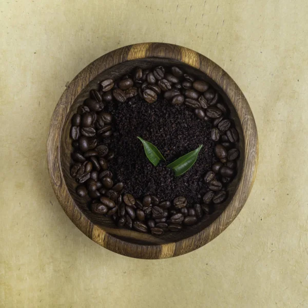 Cosméticos caseiros com esfoliação de café em tigela de madeira no fundo ecológico amarelo, folhas de flores verdes. Close-up — Fotografia de Stock