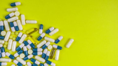 Sarı arka planda renkli haplar, kapsüller ve haplar, eczane ve sağlık sigortası konsepti. Karışık vitaminler, probiyotikler, beslenme, yaşlanma karşıtı güzellik malzemeleri, fotokopi alanı, üst görünüm