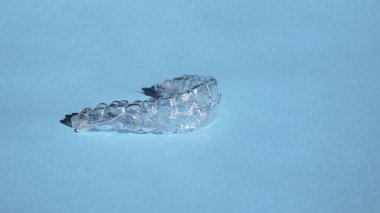 Kozmetik dişçiliğinde dişleri düzeltmek için modern diş saydam hizalayıcılar veya diş telleri ve mavi arka planda ortodonti, boşluğu kopyala