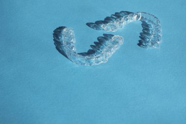 Kozmetik dişçiliğinde dişleri düzeltmek için modern diş saydam hizalayıcılar veya diş telleri ve mavi arka planda ortodonti, boşluğu kopyala