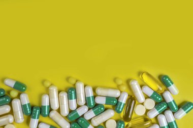 Sarı arka planda renkli haplar, kapsüller ve haplar, eczane ve sağlık sigortası konsepti. Karışık vitaminler, probiyotikler, beslenme, yaşlanma karşıtı güzellik malzemeleri, fotokopi alanı, üst görünüm