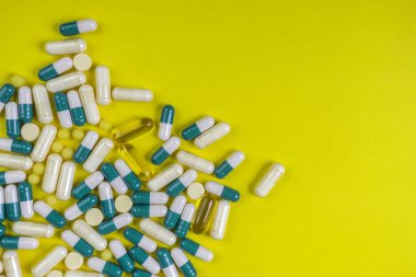 Sarı arka planda renkli haplar, kapsüller ve haplar, eczane ve sağlık sigortası konsepti. Karışık vitaminler, probiyotikler, beslenme, yaşlanma karşıtı güzellik malzemeleri, fotokopi alanı, üst görünüm