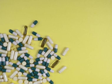 Sarı arka planda renkli haplar, kapsüller ve haplar, eczane ve sağlık sigortası konsepti. Karışık vitaminler, probiyotikler, beslenme, yaşlanma karşıtı güzellik malzemeleri, fotokopi alanı, üst görünüm