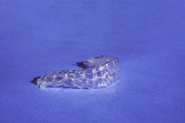 Plastik diş teli diş koruyucularını ya da hizalayıcıyı çalıştır. Güzel bir gülümsemeye, düzgün ve beyazlatıcı dişlere sahip olmanın bir yolu. Dişlerini düzelt. Mavi arka planda kozmetik dişçiliği ve ortodonti konsepti.