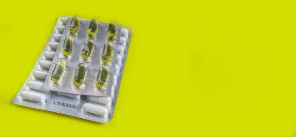 Capsules and pills packed in blisters on yellow background. Tablets. Medicine symbol. Medications drugs. Copy space