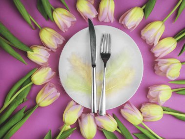 Lüks paskalya sofra takımları bıçak, çatal, pembe yüzey üzerinde renkli laleler. Tatil arkaplanı, tebrik kartı, kapat