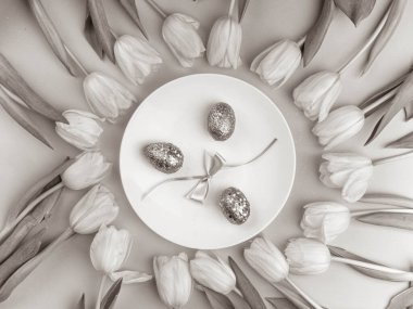 Paskalya için tek renkli kompozisyon lale, beyaz tabak ve boyalı yumurta. Üst Manzara. Mutlu Paskalyalar