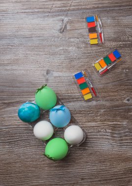 Paskalya yumurtaları ve ahşap arka planda renkli boya ve fırçalar. Resim yapmaya başlıyorum. Boşluğu kopyala