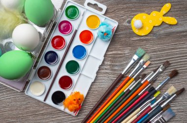 Paskalya yumurtalarının seçici odak noktası ve renkli boya ve fırçalar, ahşap arka planda tavşan. Resim yapmaya başlıyorum. Boşluğu kopyala