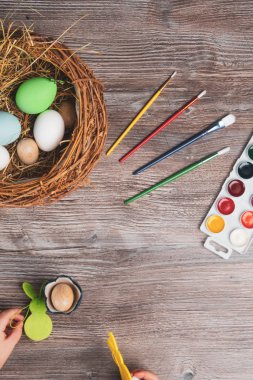 Yuvada paskalya yumurtası, tavşancık ve ahşap arka planda renkli boya ve fırçalar. Bebek Paskalya için hazırlanıyor Seçici odağı kapat