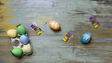 Yaratıcı tonlu paskalya yumurtaları ve ahşap arka planda renkli boya ve fırçalar. Resim yapmaya başlıyorum. Boşluğu kopyala