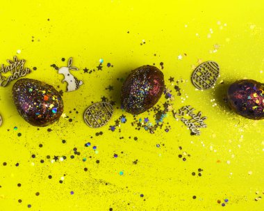 Sarı renkli arka plan, Paskalya arkaplanı veya paskalya konsepti üzerine akrilik boyalı yumurta içeren paskalya tahtası ve altın kırmızısı. Boşluğu kopyala, üst görünüm, düz uzanma