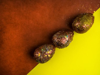 Lüks paskalya yumurtaları soyut yenilikçi akrilikle boyanmış ve çok renkli arka planda şenlikli parıltılarla süslenmiş, kırmızı altın ve sarı. Seçici odak