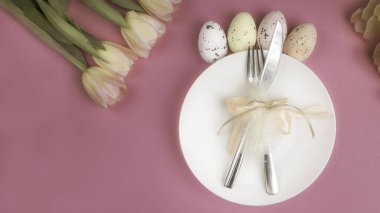 Lüks paskalya sofra takımları bıçak, çatal, pembe yüzey üzerinde renkli laleler. Tatil arkaplanı, tebrik kartı, kapat