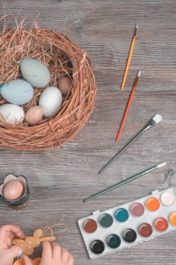 Bebek elleri Paskalya masasında, yumurta yuvası ve boyalarla, Paskalya için hazırlanan mutlu paskalya konsepti,.