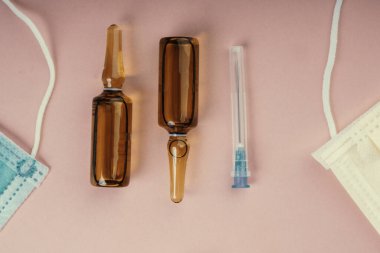 Pembe arka planda koruyucu yüz maskeleri, terapi, virüs gribinin önlenmesi, haplar, ampuller, cam, antibiyotikler, iğne, tıbbi eczane konsepti,