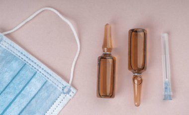 Pembe arka planda koruyucu yüz maskeleri, terapi, virüs gribinin önlenmesi, haplar, ampuller, cam, antibiyotikler, iğne, tıbbi eczane konsepti,