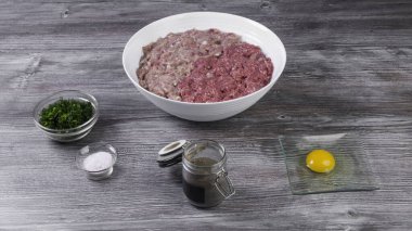 Pirzola ya da hamburgeri çiğ et ve domuz eti olarak ahşap doğrama tahtasında, soğan, dereotları, tuz, biber, yumurta, woden arkaplanda taze kıyma