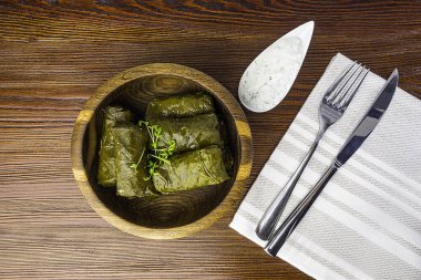 Dolma sarma ya da tolma doldurulmuş üzüm yaprakları, pirinç, et ve beyaz sos kreması, dereotlu, maydanozlu, ahşap masa üzerinde, peçeteli otlar. Geleneksel Kafkas, Türk ve Yunan mutfağı