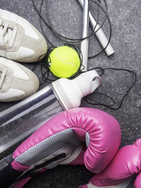 Spor ayakkabıları, deri boks eldivenleri, ip atlama, tenis topu, bir şişe su.