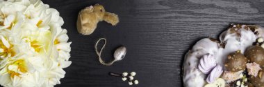 Çikolata söğüt dalları, yumurta, simit, siyah ahşap arka planda narsist çiçekler, mutlu Paskalya tebrik kartları, bahar festivali sezonu. Düz konum, üst görünüm, kopyalama alanı