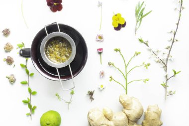 Kil fincanda papatya çayı, bitkisel çiçekler ve yaprak, zencefil ve limon, doğal bitkisel ilaçlar ve homeopatik ilaçlar, üst görüş. Düz yatıyordu.