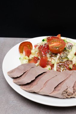 Domatesli çiğ dil ve salata, salatalık, yağ ve bembeyaz tabakta tahterevalli tohumlar.